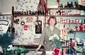 En kvinna står bakom disken i en speceriaffär, troligtvis vid eller i närheten av Gamla Torget i Mölndal, 1970-tal.

För mer information om bilden se under tilläggsinformation.