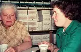 Två kvinnor sitter och fikar i Rasmussons skoaffär med adress Kvarnbygatan 4 vid Gamla Torget i Mölndal, 1970-tal. Till vänster ses tant Karin, d.v.s. Karin Gren, ägare av skoaffären, till höger Märta Sjöberg.

För mer information om bilden se under tilläggsinformation.