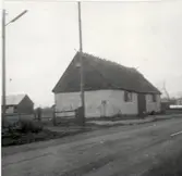 En ladugård med halmtak, takryttare och kalkstensvägg.