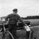 En brevbärare med sin cykel lämnar tidningen Jönköpings Posten i en brevlåda.