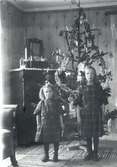 Två flickor framför en klädd julgran.