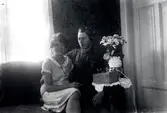 Fotograf Emil Karlsson i hemmet Ekudden lyssnande på radio tillsammans med okänd dam.