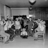 En grupp med barn sitter på stolar i en barnverksamhet.