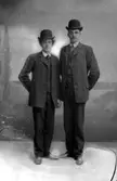 Ateljébild, två män i kostym och hatt.
Bilden missfärgad brun, emulsionsavlossning.