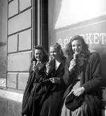 En trio unga damer med glass i vårsolen utanför apoteket Örnen på Kungsgatan 14 1945.