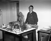 Handelsbolaget Karl Olssons chaufför bakom ett bord med tyska militärattiraljer av okänt ursprung. Bilden togs 1940.