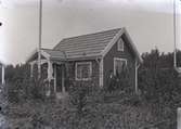En stuga och en man i Kalmar södra koloniområde, fotograferat omkring 1930. Kalmar södra koloniförening grundades 1917 och har idag 105 kolonilotter. Området ligger strax söder om länssjukhuset i Kalmar med huvudingång från Stensbergsvägen.