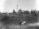 Pojke paddlar kanot utanför Hamrånge kyrka.