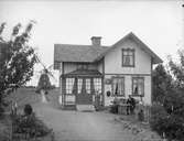 En och en halvplans vinkelbyggt bostadshus med glasad veranda. Tre personer framför byggnaden. Väderkvarn.
Mjölnaren Pettersson.
Personer på bilden, från vänster: Lilly Pettersson, 1898-1976 (gift Fahlander), Tore Pettersson 1911-1981, Elin Pettersson, 1874-1967, född Persdotter, Anders Petter Pettersson 1871-1940 och Ragnar Pettersson 1904-1980.