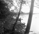 Axel Lindkvist metar i Malmjärn. Åsmundshyttan. En stilla stund vid sjön med metspöet. Bilden finns med i Torsåkers Fotohistroriska Sällsakp. Bild 5:9.