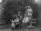 Det här är antagligen på en gård i Strömsbro. Det är farmor Kerstin Brundin sittande i mitten och bakom henne David Brundin med dottern Eva. Övriga är släktingar till Einar Olssons hustru Ellen.