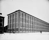 Gävle Ångväveri AB. Åkargatan 87. Industribyggnaden vid Textilgatan. Gefle Ångväfveri AB startades 1862 av Eric Sjöström. Företaget flyttade 1878 till Åkargatan med plats för 100 vävstolar och en ångkraftanläggning för driften. 1912 blev Hugo Müller disponent och lät uppföra en ny byggnad som stod klar 1918 och var mycket modern i utformning och konstruktion. Kvarteret byggdes ut 1927, med färgeri och 1934 med sidenväveri.
