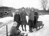 Barn med kälke i snön. Tidsomfånget är 1900 - 1940