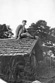 John Bauer sitter på taket till en gammal lada.