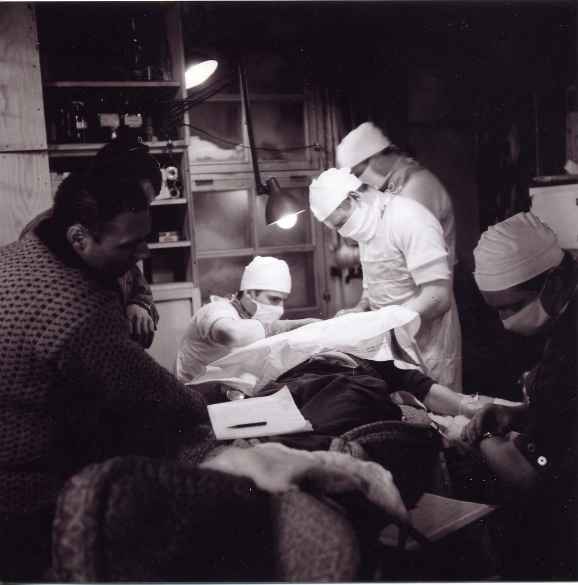 Stig Hallgren, "Under operationen av Allans öga, från vänster Gösta Liljequist, meteorolog, Ove Wilson, läkaren, Fred Roots geolog och bakom honom står Valter Schytt glaciolog, längst till höger Stig Hallgren fotograf, ger narkos."
