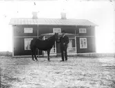 Man med häst utanför bostad.