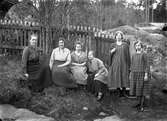 Fem kvinnor och en flicka vid ett staket.