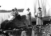 Fyra kvinnor på stranden, roddbåt (snipa) i bakgrunden.