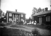 Gruppbild framför bostadshus, Karl Jonsson med boskap. Pojkarna okända, damerna från vänster: Beda Viberg, okänd, fröken Anna Blomberg (bodde i den lilla stugan) och fröken Mina Jonsson, syster till Karl, hade affär på Vifors. Foto tidigt 1900-tal.