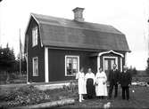 Familj framför bostadshus, okänd plats.