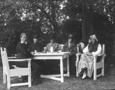 Damer vid ett kaffebord, utomhus.