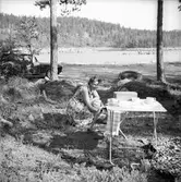 Kvinnan gör iordning fika vid campingbordet
