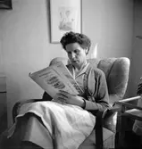 Okänd kvinna läser tidning
