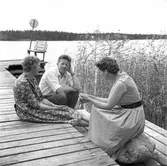 Två kvinnor en man sitter på bryggan

