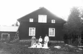 Familj samlad framför gårdsbyggnad. Foto 1917.