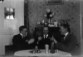 Suddig bild, tre män som dricker snaps.