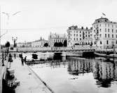 Centralbron, en träbro på järnstomme i två spann invigdes 1901 som förband Norra och Södra Centralgatan.

I Gavleån ligger en ångbåt och andra småbåtar.
Parkbänkar vid kajkanten där trälådor och mjölkkruka väntar på transport

