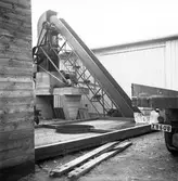 Gävlefisks nybyggda fastighet. 20 oktober 1950. Bilden visar en s.k elevator för isblock (naturis) som tagits fram från isstacken till vänster och sköljts från spån i rundeln som är ett vattenkar. Elevatorn transporterar isblocken upp till luckan och faller sedan ner i en kross och blir till krossad is att ha i fisken.