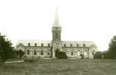 Borgholms kyrka på ett foto från 1906. En buske skymmer en del av kyrkporten.