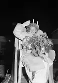 Mary Forslund, Gävle Lucia 1949. Hon är 21 år och handhar arkivet hos A/B Carl Larssons fotografiska atelier Tärnorna är Margareta Svensson, Harriet Jansson, Ulla Persson och Marianne Lundin. Luciatåget startar från Brandstation och går Nygatan - N. Skeppargatan - Drottninggatan - Stora Esplanadgatan och åter till Brandstationen. Soaré på teatern som arrangerat av köpmanna- och hantverkarungdomen i Gävle, leds av Macce Kjellin, kröntes Lucian med smycket av direktör Gösta Nygren, Furuvik. Lucia tävlingen arrangerades av Norrlands-Posten.
