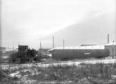 Bilden föreställer ett av Gävle - Dala Järnväg hembyggt motorlok med nummer 1165. På bilden drar det en tank av något slag, troligen en tank för impregnering av järnvägsslipers eller telefonstolpar. Gävle Varv. Autoklav. 27 november 1945.