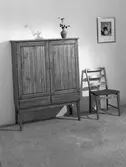 Skåp, stol, tavla och en blomvas. Den 18 oktober. Ahrnebergs