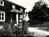 Två äldre kvinnor med ett barn utanför ett hus i  Hasselås