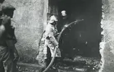 Ångkvarnen i Kalmar. Branden juli månad 1935. Brandmän sprutar vatten när folk kollar på.