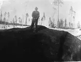 Man med spade som står på en kulle.