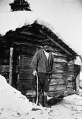 Man, utanför stuga.