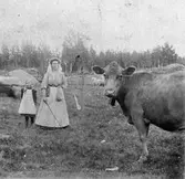 En kvinna och en liten flicka, som vallar kor.