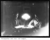 Fotografen och Ivar läser i lampskenet.