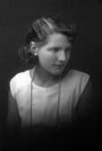 Ateljébild på en kvinna i klänning och halsband. Enligt Walter Olsons journal är bilden beställd av Greta Hermansson.
