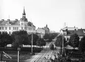 Nygatan vid järnvägsövergången. Spårvagn väntar vid fällda bommar.