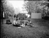 Män och kvinnor har picknick vid tältet, Sverige