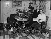 Kvinna och man omgiven av blommor i bostadsmiljö, Östhammar, Uppland