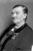 Ateljébild på Kristvalla sockens barnmorska Britta Österström. Hon tjänstgjorde i Kristvalla 1880-1930 och fick vid sin avgång medalj för lång och trogen tjänst. Britta Österström levde 1855-1937.