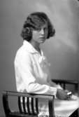 Ateljébild på en kvinna i klänning, sittandes på en pall. Enligt Walter Olsons journal är bilden beställd av Lundin Harriet ifrån Grimskär.