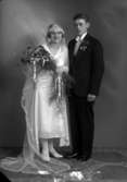 Bröllopsbild på ett okänt par. Kvinnan har en blombukett och har på sig en brudklänning, mannen i kostym.