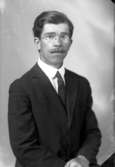 Ateljébild på en man i kavaj och glasögon. Enligt Walter Olsons journal är bilden beställd av herr E Fransén.